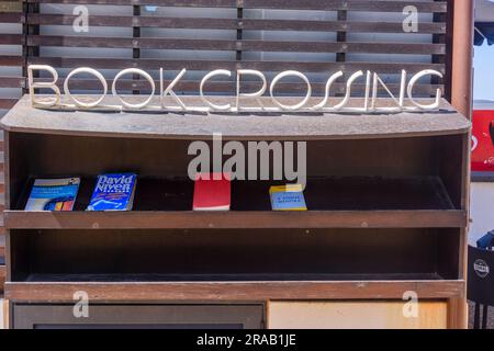 Le panneau « livre croisant » sur une étagère, encourageant les gens à échanger des livres. Banque D'Images