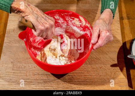 Une femme cuisinier mélange la pâte à l'aide d'une spatule en préparation de la fabrication du pain de soda irlandais Banque D'Images