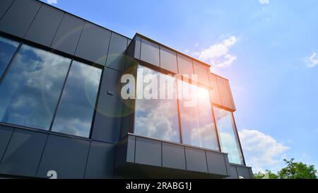 Façade en graphite et grandes fenêtres sur un fragment d'immeuble de bureaux contre un ciel bleu. Façade moderne en aluminium avec fenêtres. Banque D'Images