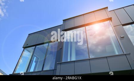 Façade en graphite et grandes fenêtres sur un fragment d'immeuble de bureaux contre un ciel bleu. Façade moderne en aluminium avec fenêtres. Banque D'Images