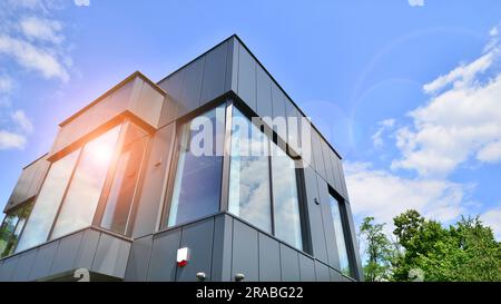 Façade en graphite et grandes fenêtres sur un fragment d'immeuble de bureaux contre un ciel bleu. Façade moderne en aluminium avec fenêtres. Banque D'Images