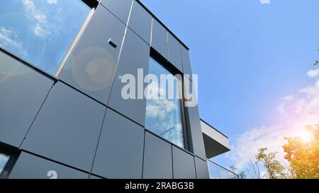 Façade en graphite et grandes fenêtres sur un fragment d'immeuble de bureaux contre un ciel bleu. Façade moderne en aluminium avec fenêtres. Banque D'Images