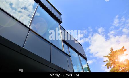 Façade en graphite et grandes fenêtres sur un fragment d'immeuble de bureaux contre un ciel bleu. Façade moderne en aluminium avec fenêtres. Banque D'Images