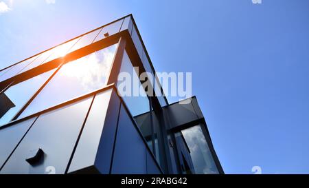 Façade en graphite et grandes fenêtres sur un fragment d'immeuble de bureaux contre un ciel bleu. Façade moderne en aluminium avec fenêtres. Banque D'Images