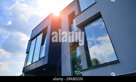 Façade en graphite et grandes fenêtres sur un fragment d'immeuble de bureaux contre un ciel bleu. Façade moderne en aluminium avec fenêtres. Banque D'Images