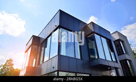 Façade en graphite et grandes fenêtres sur un fragment d'immeuble de bureaux contre un ciel bleu. Façade moderne en aluminium avec fenêtres. Banque D'Images