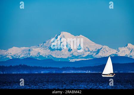 Téléobjectif en gros plan d'un voilier devant un mont enneigé Baker, Cascade Range, Washington, États-Unis Banque D'Images