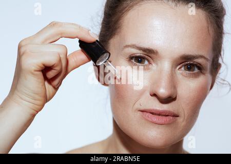 jeune femme de 40 ans avec élixir cosmétique isolée sur blanc. Banque D'Images