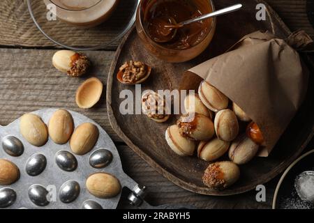 Petits gâteaux faits maison en noyer fraîchement cuits, lait concentré cuit, plat de cuisson et une tasse de café sur une table en bois, plat Banque D'Images