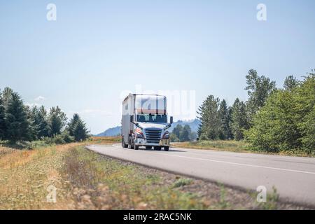 Cabine de jour blanche industrielle grand capot de l'engin semi-camion classique transportant des marchandises commerciales dans une semi-remorque en vrac couverte conduite sur l'été étroit sce Banque D'Images