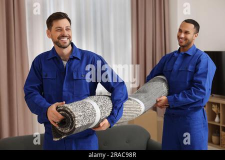 Hommes déménageurs portant tapis dans la nouvelle maison Banque D'Images