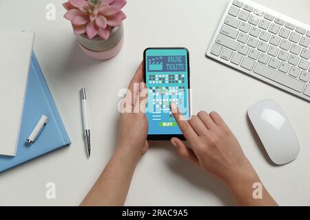 Femme achetant des billets de cinéma en ligne par téléphone portable à table, vue de dessus Banque D'Images
