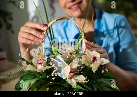Magnifique arrangement de fleurs dans le panier en osier dans les mains d'une femme souriante floue, pour événement de vie festive. Concept « Happy Women's Day » ou « Other's Day » Banque D'Images