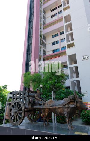 Statue du patrimoine de l'homme assis sur une charrette à boulette au pied du bloc d'appartements de logements publics à Buffalo Road, Little India, Singapour Banque D'Images