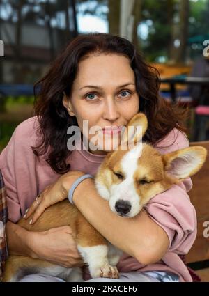 Portrait de belle jeune femme brune tenant son chien corgi et regardant la caméra Banque D'Images