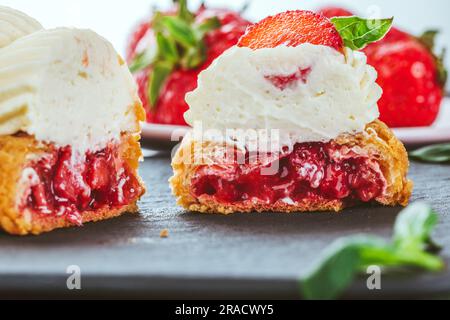 eclair français, grasé de chocolat et de crème fruitée aux fraises ou de doux profiteroles italiens et de fraises juteuses fraîches, de la nourriture fraîche backgrou d'été Banque D'Images