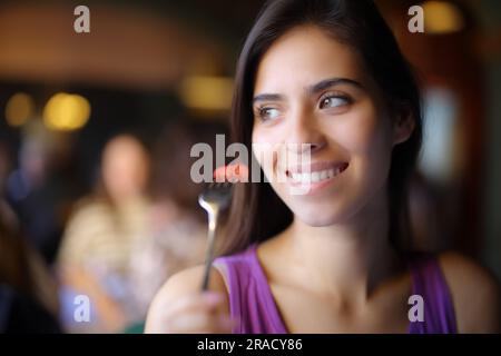 Bonne femme mangeant des fraises et regardant à côté dans un restaurant Banque D'Images