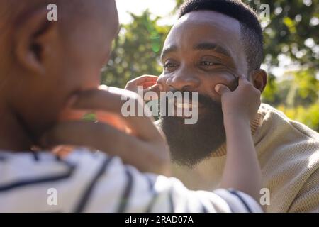 Gros plan du père afro-américain et son fils touchant les joues dans la cour le jour ensoleillé Banque D'Images