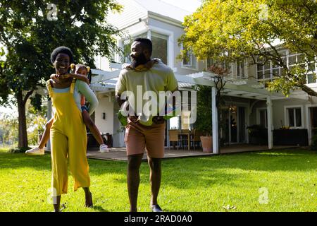 Heureux parents afro-américains piggybacking joueur fils et fille tout en marchant dans la cour Banque D'Images