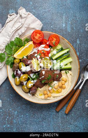 Bol de falafel avec houmous, légumes, olives, herbes et sauce au yaourt Banque D'Images