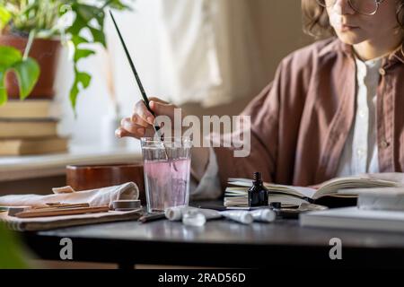 L'artiste peint avec des acryliques nettoie la brosse dans le verre transparent de l'eau. Espace esthétique pour la créativité Banque D'Images