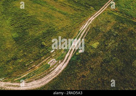 Photographie aérienne de la route de terre courbe à travers la prairie verte, drone pov vue à grand angle Banque D'Images