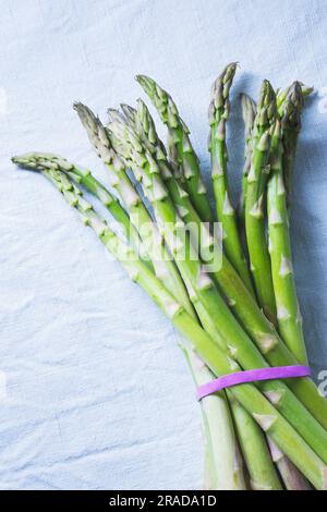 Un paquet d'asperges vertes sur une nappe blanche Banque D'Images