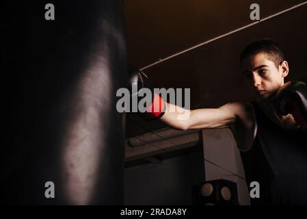 Boxeur jeune homme pratiquant une boxe à succès pendant l'entraînement. Banque D'Images