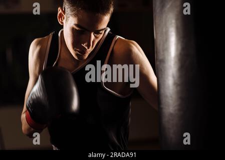 Gros plan d'un jeune boxeur pratiquant une boxe à succès pendant l'entraînement. Banque D'Images