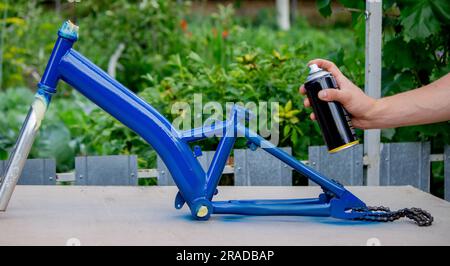 le père peint le vélo de l'enfant avec de la peinture bleue. mise au point sélective Banque D'Images