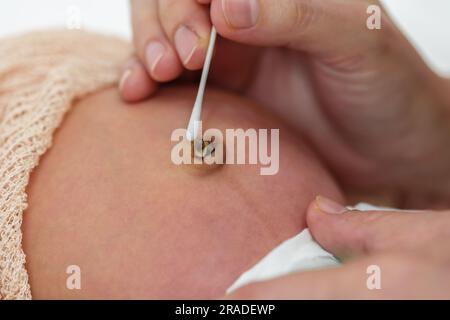 fermez la mère à l'aide d'un coton-tige humidifié avec de l'alcool pour nettoyer le bébé du cordon ombilical du nombril Banque D'Images