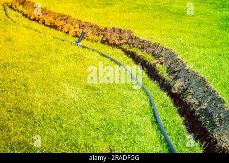 Auto-installation de l'irrigation avec un arroseur rétractable dans la pelouse finie. Pose de conduites d'eau avec des pulvérisateurs sous la pelouse pour l'irrigation. Banque D'Images