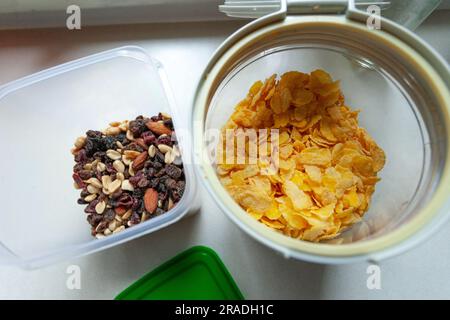 Friandises et cornflakes dans des récipients en plastique sur le plan de travail de la cuisine, vue de dessus Banque D'Images