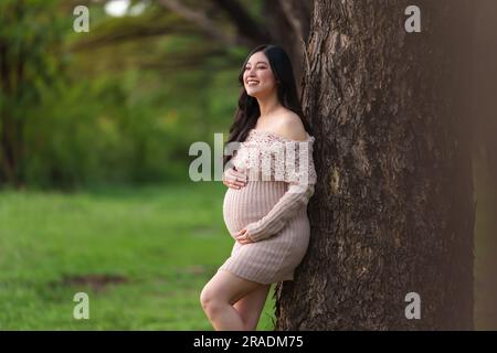 jeune belle femme enceinte qui a caressé son ventre dans le parc Banque D'Images