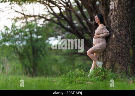 jeune heureuse belle femme enceinte qui a caressé son ventre dans le parc Banque D'Images