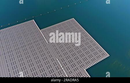 La vue aérienne présente un vaste éventail de panneaux solaires, créant une énergie alternative visuellement saisissante à la surface du lac. Banque D'Images