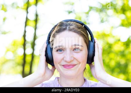 Mélodic Bliss : Close-Up Portrait d'une belle Brunette perdue dans musical Delight, gros plan portrait d'une belle brune mignonne écoutant de la musique à travers des écouteurs et souriant de plaisir. Photo de haute qualité, admirez la joie pure et l'enchantement tandis qu'une belle brune s'adonne à la magie de la musique, capturée dans ce portrait en gros plan. Avec des écouteurs ornant gracieusement ses oreilles, elle se plonge dans la symphonie mélodique, son visage rayonnant d'un sourire authentique de pur plaisir. Ses yeux expressifs scintillent de délice, reflétant les émotions évoquées par la musique. Rayonnant la beauté et c Banque D'Images