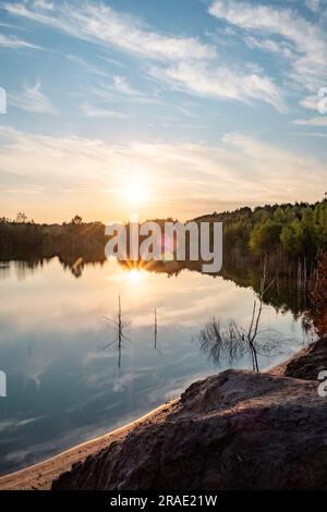 Admirez la beauté impressionnante de la nature tandis qu'un paysage époustouflant se dévoile sous vos yeux. Un coucher de soleil coloré peint le ciel avec des teintes vibrantes de rouge et d'or, jetant un reflet à couper le souffle sur un lac forestier serein. Des nuages épiques, ornés de tons rouges et dorés, créent un affichage céleste qui complète le paysage enchanteur. Le lac tranquille reflète la splendeur ci-dessus, renforçant le sentiment d'émerveillement et de sérénité. Plongez dans le spectacle majestueux de ce coucher de soleil vibrant, où les éléments de la nature convergent pour créer une expérience vraiment inoubliable et captivante. Ma Banque D'Images