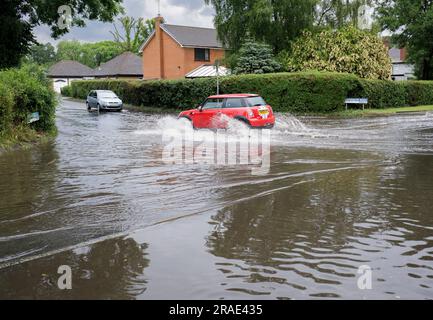 Les automobilistes qui traversent les eaux de crue après une tempête de pluie à Redditch, dans le Worcestershire. Banque D'Images