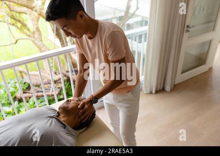 Physiothérapeute masculin diverse conseillant et faisant de l'exercice aux patients âgés Banque D'Images