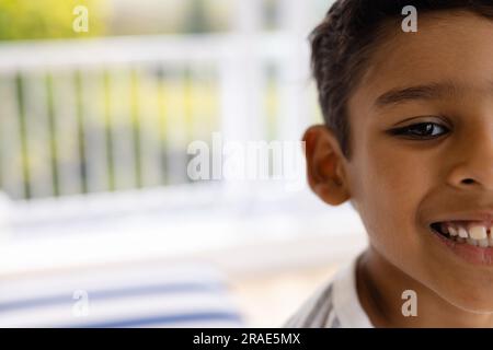 Demi portrait de garçon biracial heureux souriant dans la chambre à la maison, espace de copie Banque D'Images