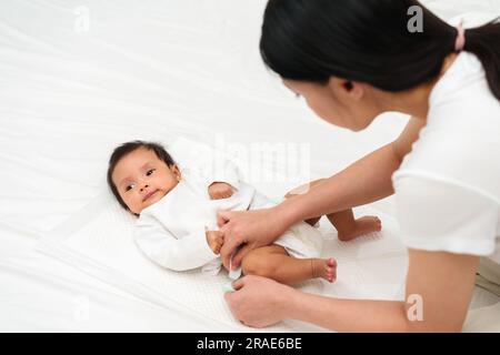 mère changeant la couche du nouveau-né en étant couché sur un lit Banque D'Images