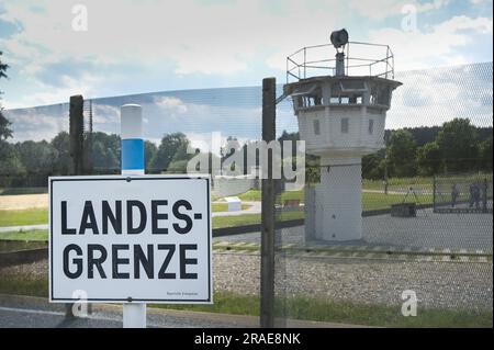 17 juin 2023, Thürigen, Mödlareuth: Une tour de guet et un panneau 'Landesgrenze' à l'ancienne frontière intérieure-allemande près de Mödlareuth. En raison de sa similarité avec le mur de Berlin, la section frontalière est également connue sous le nom de « petit Berlin ». Aujourd'hui, le mémorial allemand-allemand du Musée est situé ici. Photo: Heiko Rebsch/dpa Banque D'Images