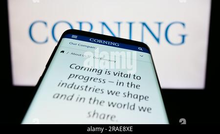Téléphone mobile avec page Web de la société technologique américaine Corning Incorporated à l'écran devant le logo de l'entreprise. Effectuez le focus sur le coin supérieur gauche de l'écran du téléphone. Banque D'Images