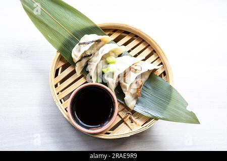 Dim Sum frit orientale avec de la viande hachée également connu sous le nom de Gyoza, Dim Sum, Jiaozi ou Momo sur une feuille de banane avec sauce épicée gros plan. Bœuf et RAM fine chaude Banque D'Images