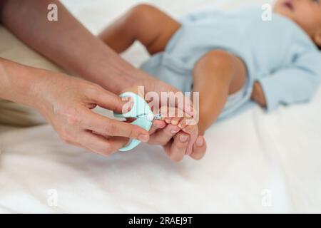 mère coupant les ongles du pied du nouveau-né avec des ciseaux à ongles. Banque D'Images