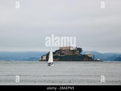 Un yacht naviguant dans la baie de San Francisco avec l'île d'Alcatraz et la prison San Francisco Californie USA Banque D'Images