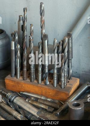 Les forets pour métal sont sur établi dans l'atelier de tournage. Rangement des outils. Arrière-plan industriel. Banque D'Images