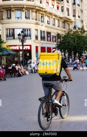 Valence, Espagne - juin 2023 : pilote Glovo, livreur sur un vélo qui va livrer une commande. Service de livraison d'applications Glovo Banque D'Images