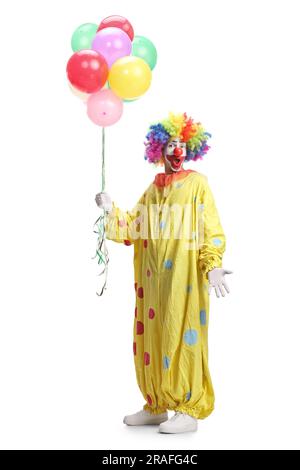 Portrait complet d'un clown en costume jaune tenant des ballons isolés sur fond blanc Banque D'Images